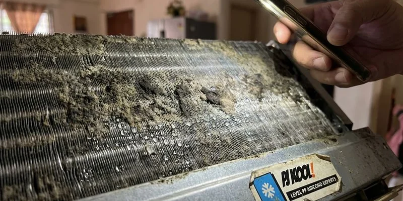 Close up view of dirty aircond evaporator coil covered in mould and grime before chemical wash treatment in tropical climate