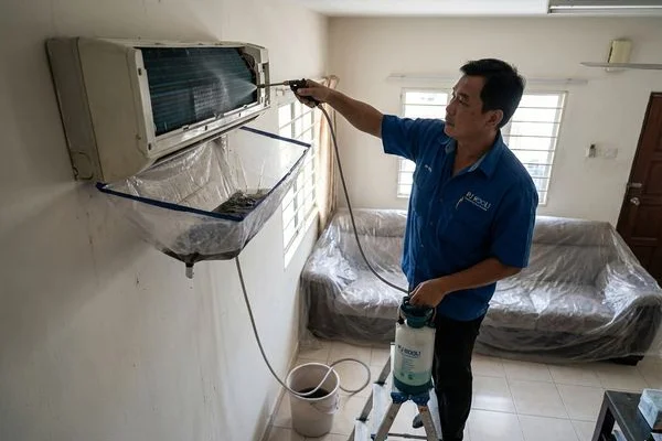 PJ Kool technician performing chemical wash on wall-mounted aircond unit